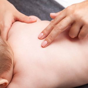 Seven month baby girls spine being manipulated by osteopathic or chiropractic manual therapist